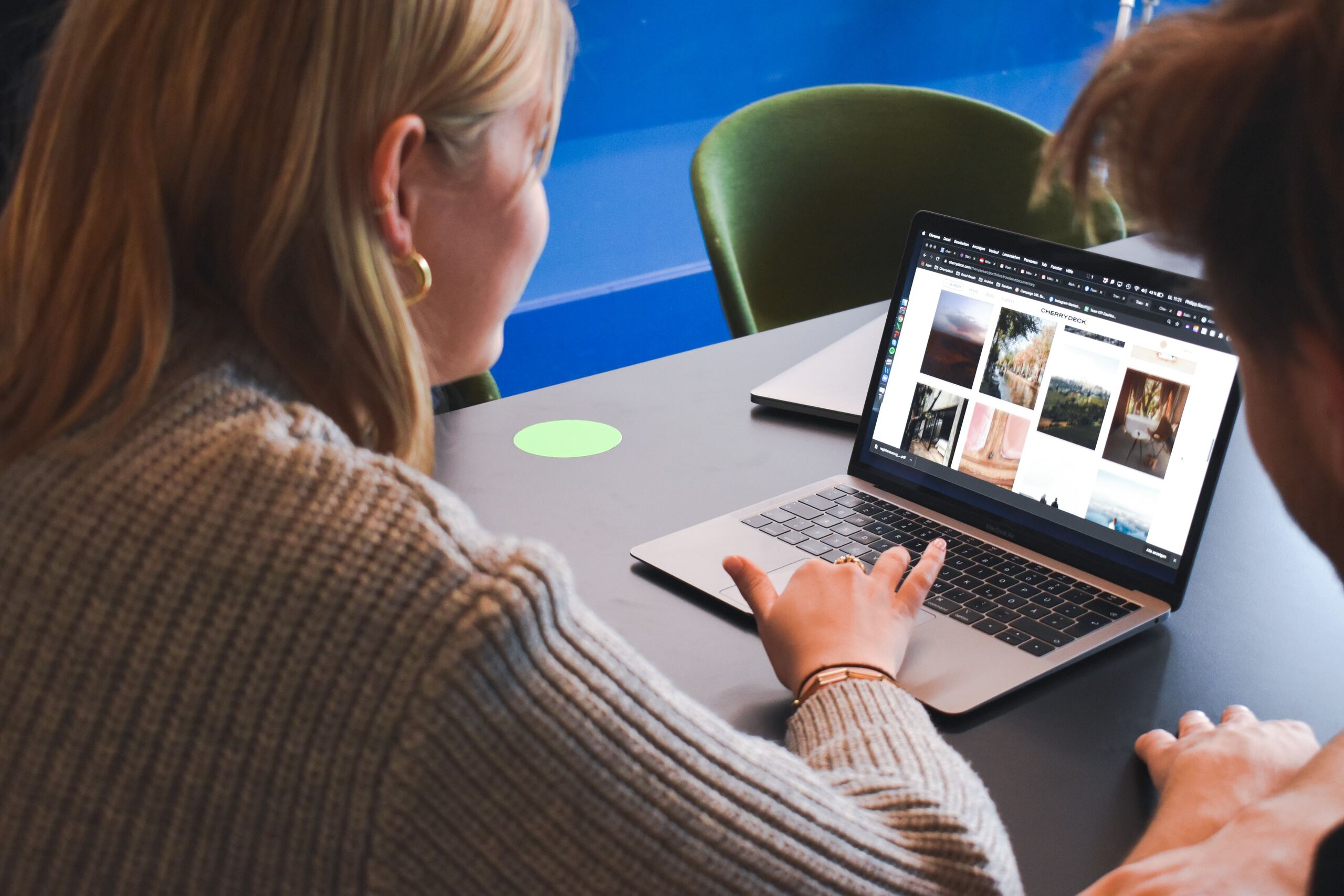 woman in gray sweater using macbook pro