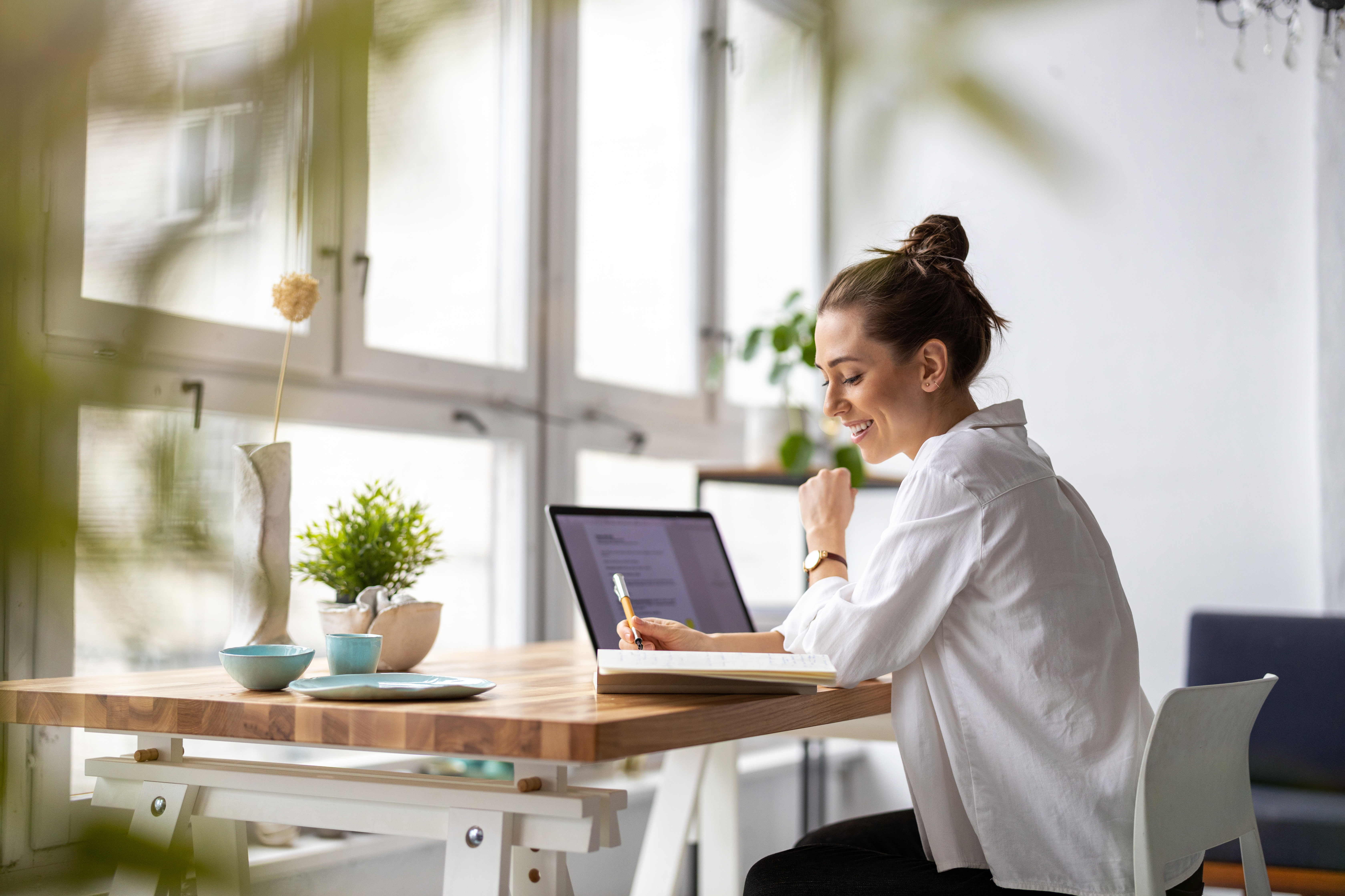 Smiling woman with white blouse sitting on desk working